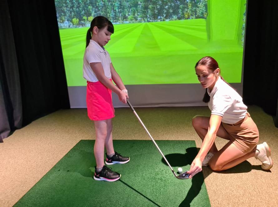 Athletic woman trainer teaches teenage girl child to play golf